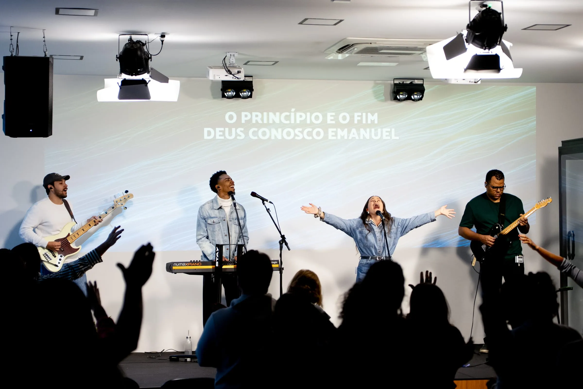Banda ministrando no palco enquanto a congregação adora de braços erguidos