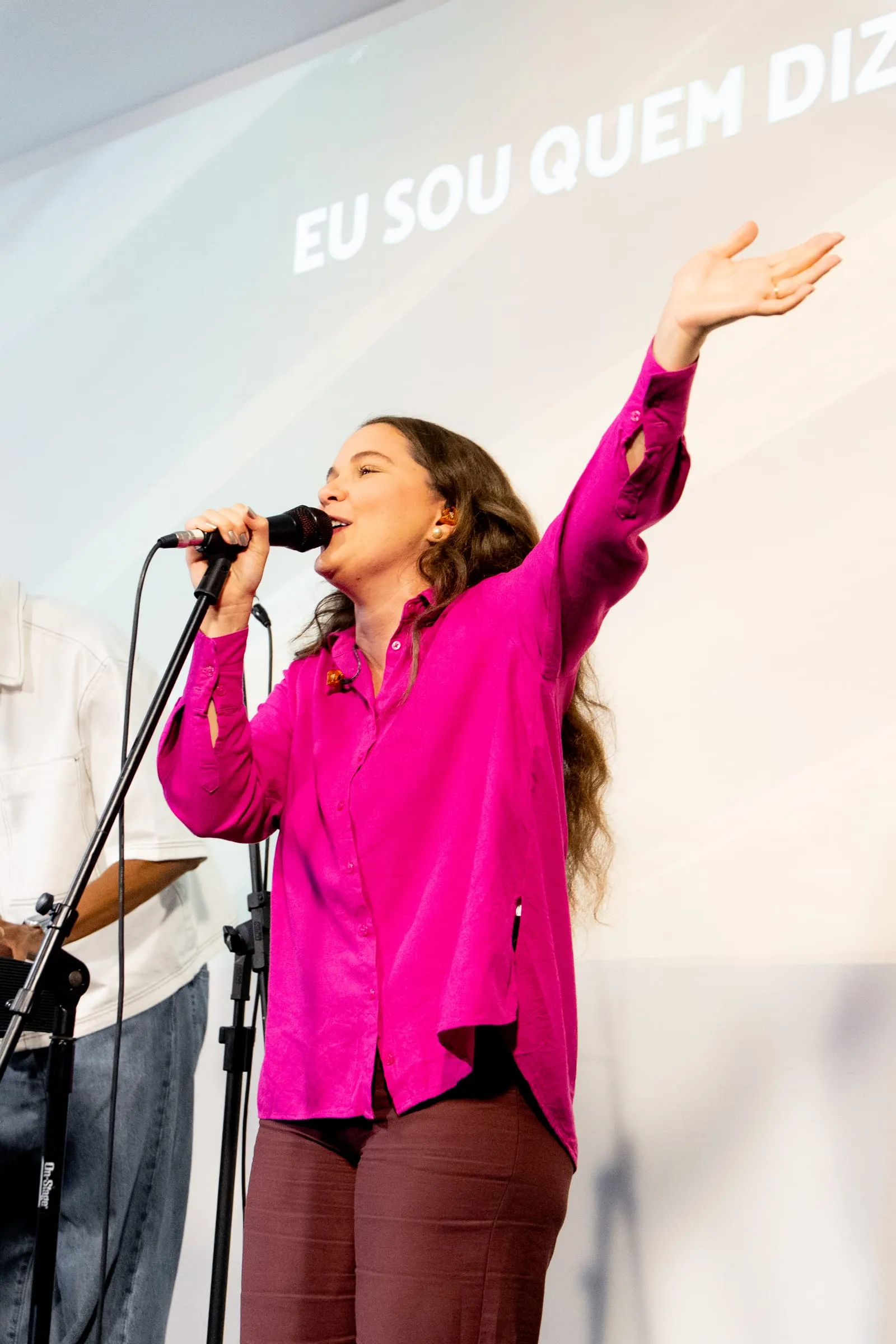 Vocalista com o braço erguido cantando durante o louvor